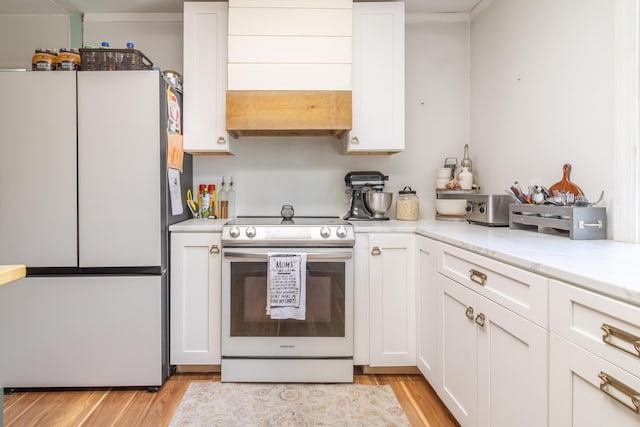 166 Franklin St, Bucksport, ME 04416 - kitchen with freestanding refrigerator, electric range, white cabinets, light wood finished floors, and light stone counters