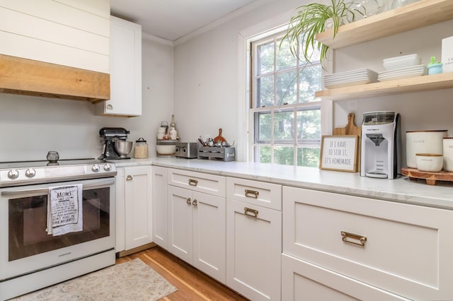 166 Franklin St, Bucksport, ME 04416 - kitchen with stainless steel range with electric stovetop, open shelves, light wood-style flooring, white cabinets, and crown molding
