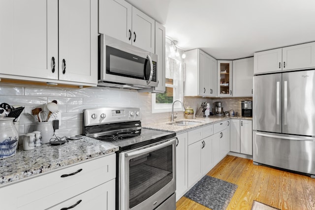 48 E Pasture Rd, Berwick, ME 03901 - kitchen featuring stainless steel appliances, a sink, light wood-style floors, glass insert cabinets, and light stone countertops