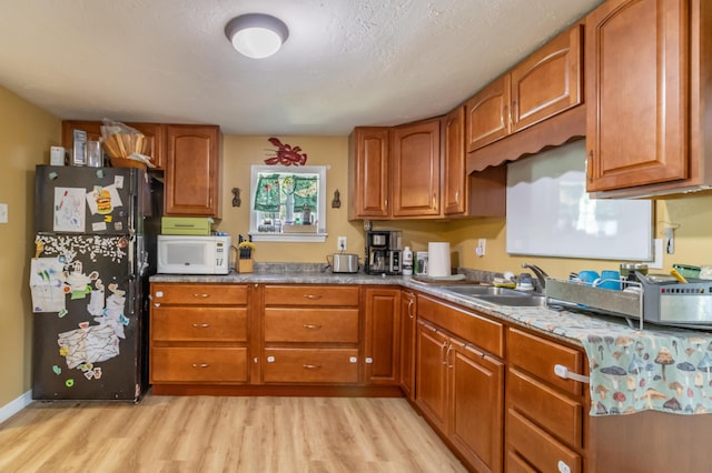 194 Main Rd, Passadumkeag, ME 04475 - kitchen featuring freestanding refrigerator, white microwave, light wood-style floors, and brown cabinetry
