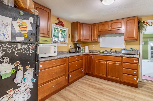 194 Main Rd, Passadumkeag, ME 04475 - kitchen with freestanding refrigerator, white microwave, light wood-style flooring, and brown cabinetry