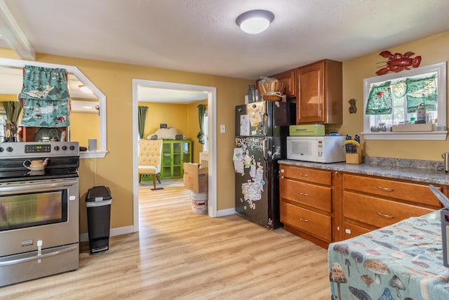 194 Main Rd, Passadumkeag, ME 04475 - kitchen with stainless steel electric stove, freestanding refrigerator, white microwave, and light wood finished floors