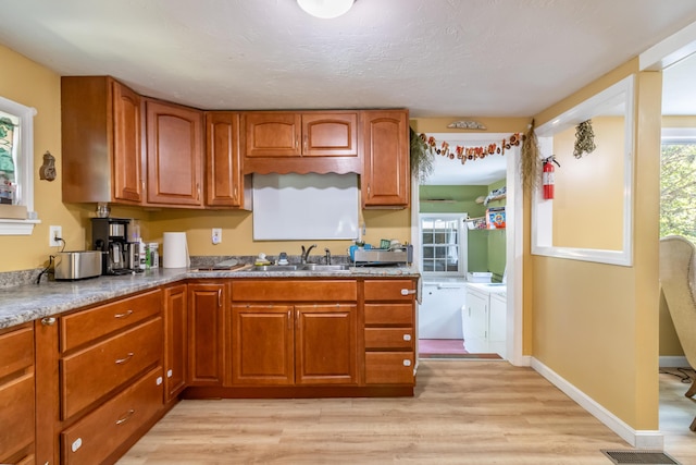 194 Main Rd, Passadumkeag, ME 04475 - kitchen featuring washing machine and dryer, light wood-type flooring, and brown cabinets