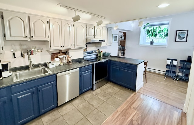245 Broadway Unit 106, South Portland, ME 04106 - kitchen with stainless steel appliances, blue cabinets, under cabinet range hood, dark countertops, and baseboard heating