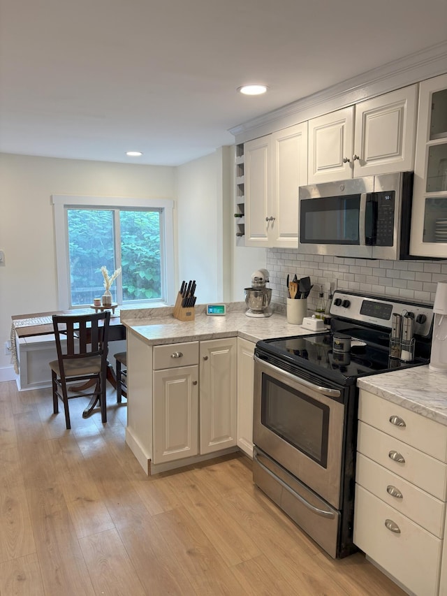 10 Valley St, Augusta, ME 04330 - kitchen with stainless steel appliances, white cabinets, light wood-style floors, a peninsula, and backsplash