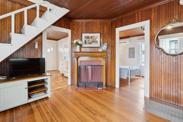 134 W Grand Ave, Old Orchard Beach, ME 04064 - living room featuring a wall mounted AC, wood walls, electric panel, wood finished floors, and a fireplace
