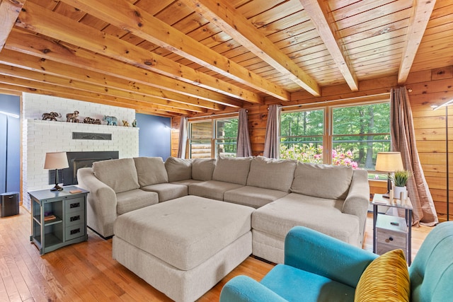 324 Pleasant Pond Rd, Turner, ME 04282 - living area with healthy amount of natural light, a wooden ceiling with exposed beams, light wood-style flooring, a fireplace, and wood walls