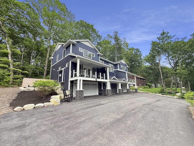 132 Mineral Spring Rd Unit 1, Windham, ME 04062 - view of front of home featuring stone siding, a balcony, view of scattered trees, an attached garage, and driveway