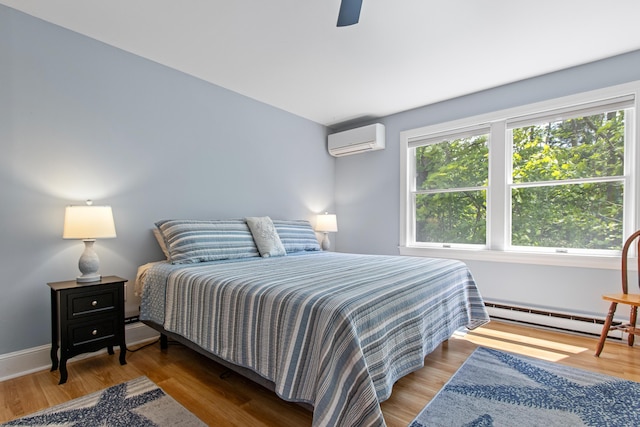 65 Pine Point Rd Unit 7, Scarborough, ME 04074 - bedroom featuring a wall unit AC, a baseboard radiator, wood finished floors, and ceiling fan