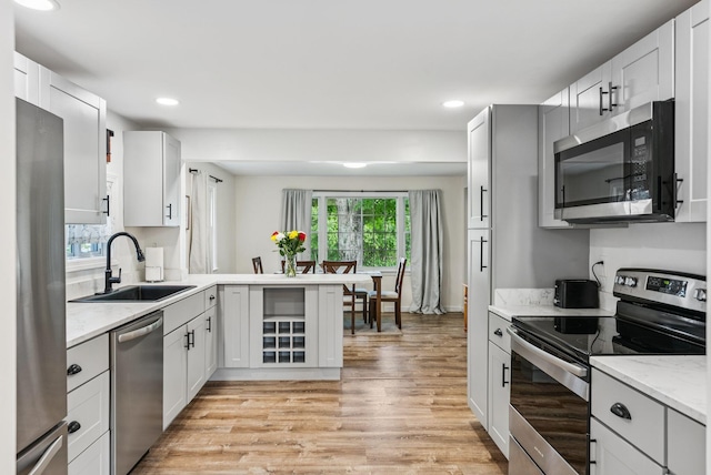 15 Bernard Ave, Biddeford, ME 04005 - kitchen with stainless steel appliances, a sink, light wood finished floors, recessed lighting, and light stone countertops