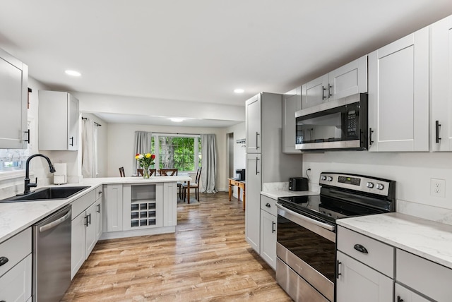 15 Bernard Ave, Biddeford, ME 04005 - kitchen with appliances with stainless steel finishes, a sink, light wood finished floors, recessed lighting, and a peninsula