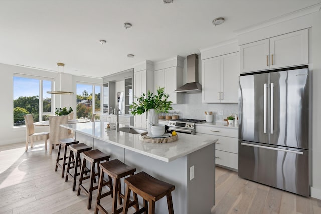 387 Commercial St Unit 527, Portland, ME 04101 - kitchen featuring appliances with stainless steel finishes, wall chimney exhaust hood, white cabinets, and a kitchen breakfast bar