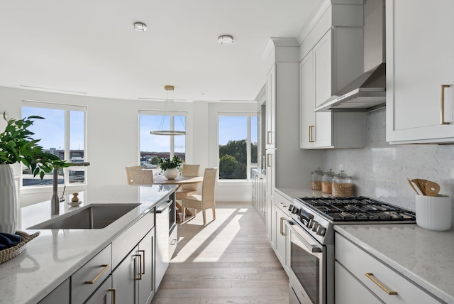 387 Commercial St Unit 527, Portland, ME 04101 - kitchen featuring appliances with stainless steel finishes, wall chimney range hood, light wood-style floors, and healthy amount of natural light