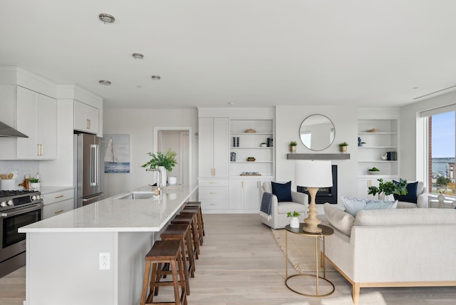 387 Commercial St Unit 527, Portland, ME 04101 - kitchen with appliances with stainless steel finishes, a kitchen breakfast bar, light wood finished floors, and white cabinetry