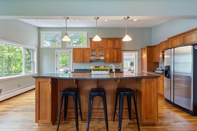 21 Glenhaven Cir W, Saco, ME 04072 - kitchen featuring appliances with stainless steel finishes, brown cabinets, a high ceiling, light wood finished floors, and a kitchen bar