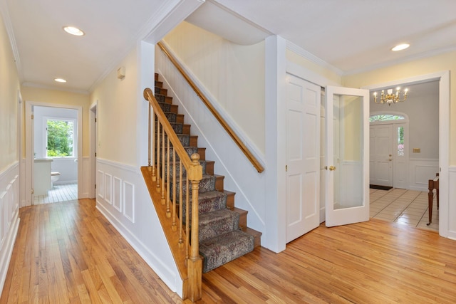 21 Glenhaven Cir W, Saco, ME 04072 - stairs with a decorative wall, ornamental molding, wood finished floors, a chandelier, and a wainscoted wall