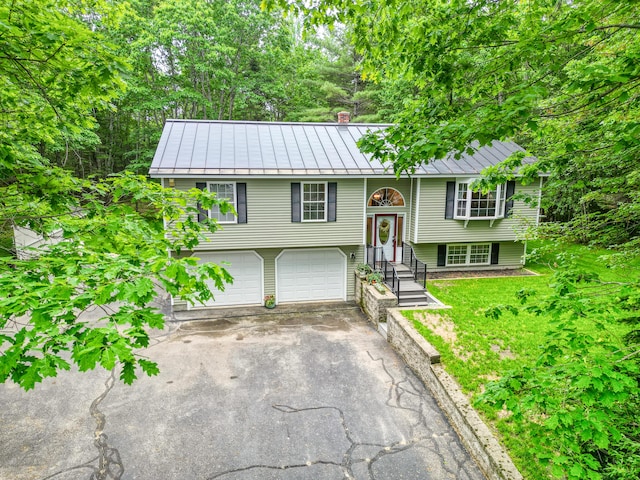 76 Bunny St, Augusta, ME 04330 - bi-level home with a standing seam roof, asphalt driveway, a garage, metal roof, and a chimney