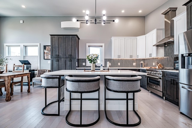 156 Oxford St, Portland, ME 04101 - kitchen featuring appliances with stainless steel finishes, tasteful backsplash, light countertops, a high ceiling, and a kitchen bar