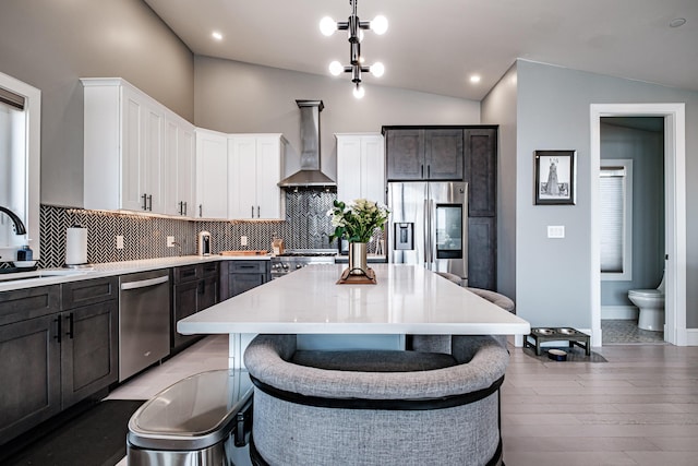 156 Oxford St, Portland, ME 04101 - kitchen featuring appliances with stainless steel finishes, wall chimney exhaust hood, vaulted ceiling, decorative backsplash, and light countertops