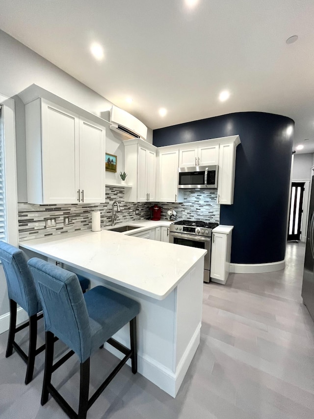 156 Oxford St, Portland, ME 04101 - kitchen featuring appliances with stainless steel finishes, a sink, a peninsula, a wall mounted air conditioner, and tasteful backsplash