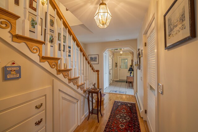 463 Seawall Rd, Southwest Harbor, ME 04679 - entrance foyer with a chandelier, arched walkways, light wood-style flooring, baseboard heating, and stairway
