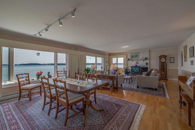 463 Seawall Rd, Southwest Harbor, ME 04679 - dining space featuring rail lighting, light wood-style flooring, ornamental molding, a brick fireplace, and a water view