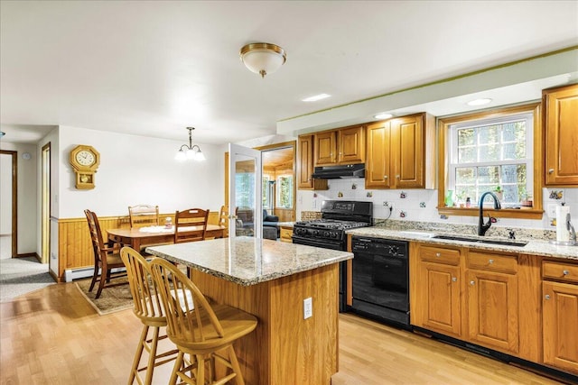 21 Heritage Ln, Orland, ME 04472 - kitchen with black appliances, under cabinet range hood, light wood-type flooring, a kitchen island, and light stone counters