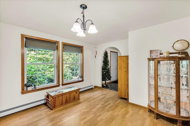 21 Heritage Ln, Orland, ME 04472 - unfurnished room featuring baseboard heating, light wood finished floors, arched walkways, and a chandelier