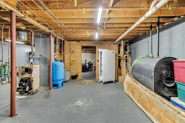 21 Heritage Ln, Orland, ME 04472 - unfinished below grade area featuring a water pressure tank, heating fuel, a heating unit, and freestanding refrigerator