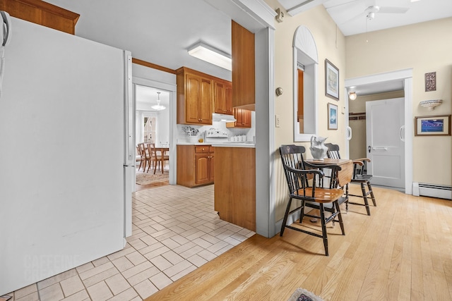 42 Sylvan Rd, South Portland, ME 04106 - kitchen with freestanding refrigerator, light countertops, brown cabinets, under cabinet range hood, and ceiling fan