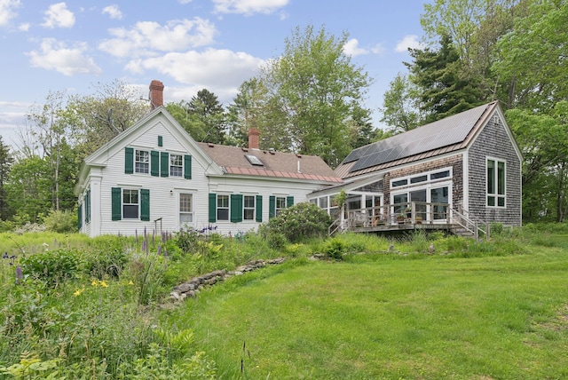 168 S Rd, Chebeague Island, ME 04017 - back of property with a chimney, a wooden deck, solar panels, and a lawn