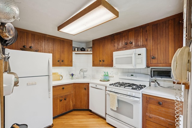 168 S Rd, Chebeague Island, ME 04017 - kitchen with white appliances, light wood-type flooring, tasteful backsplash, light countertops, and brown cabinets