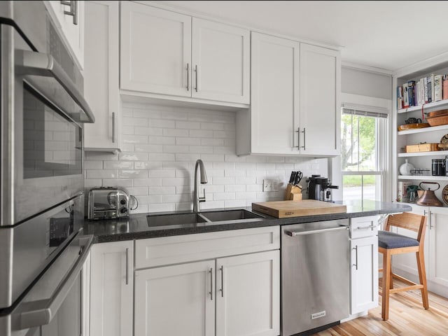 2593 Bristol Rd, Bristol, ME 04554 - kitchen featuring stainless steel appliances, decorative backsplash, white cabinetry, light wood-style flooring, and dark stone counters