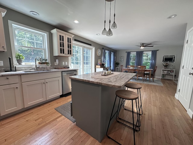 35 Knight Dr, Naples, ME 04055 - kitchen with stainless steel dishwasher, a kitchen island, a ceiling fan, a breakfast bar, and light wood-type flooring