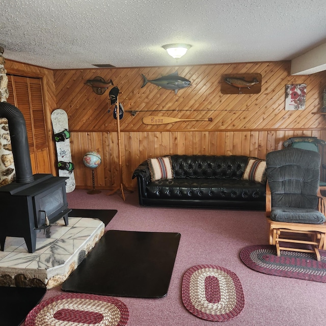 116 Main Rd, Passadumkeag, ME 04475 - carpeted living area featuring a wood stove, wooden walls, and a textured ceiling