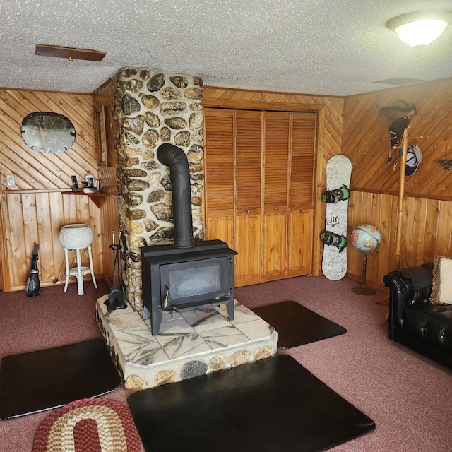 116 Main Rd, Passadumkeag, ME 04475 - living room featuring wooden walls, carpet, a wood stove, and a textured ceiling