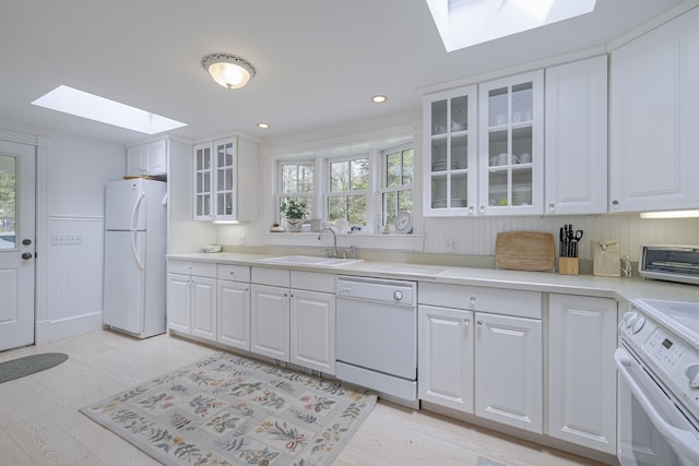 55 Ferry Rd, Swans Island, ME 04685 - kitchen with a skylight, white appliances, a sink, light wood-style flooring, and white cabinetry