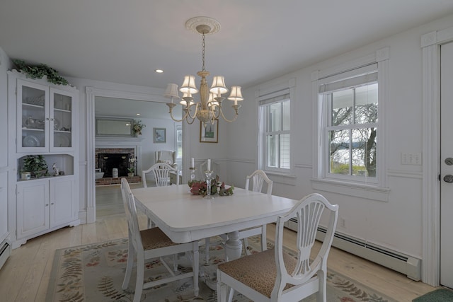 55 Ferry Rd, Swans Island, ME 04685 - dining space with a chandelier, light wood-type flooring, a baseboard heating unit, a brick fireplace, and recessed lighting