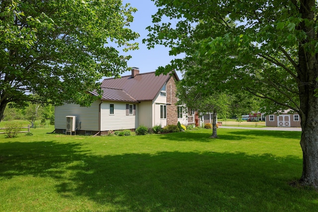 178 Clinton Ave, Winslow, ME 04901 - view of side of home with a chimney, a standing seam roof, a lawn, and metal roof