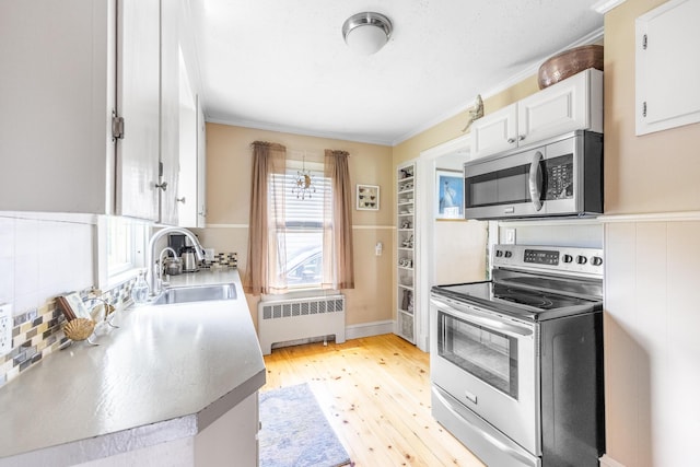 32 Carroll St, Old Town, ME 04468 - kitchen featuring radiator heating unit, appliances with stainless steel finishes, a sink, crown molding, and white cabinets
