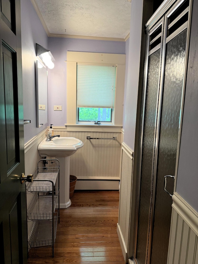 190 Belfast Rd, Camden, ME 04843 - bathroom with wainscoting, wood-type flooring, ornamental molding, a textured ceiling, and a baseboard heating unit