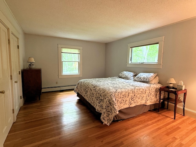 190 Belfast Rd, Camden, ME 04843 - bedroom featuring a baseboard radiator, multiple windows, wood finished floors, and a textured ceiling