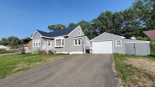 177 Ohio St, Millinocket, ME 04462 - view of front facade featuring an outdoor structure, a garage, a standing seam roof, metal roof, and driveway