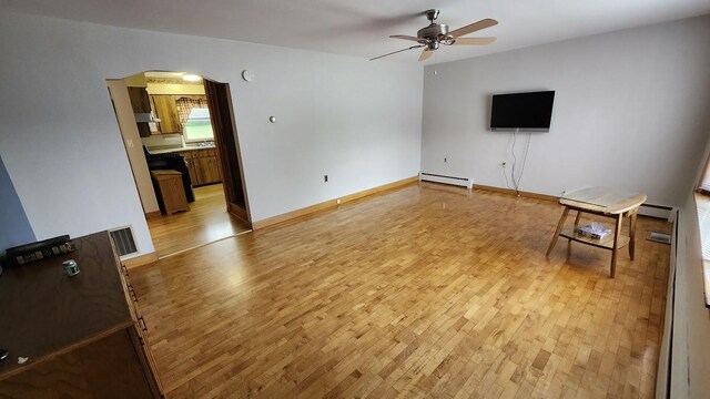 177 Ohio St, Millinocket, ME 04462 - unfurnished living room with a baseboard radiator, light wood-type flooring, ceiling fan, and arched walkways