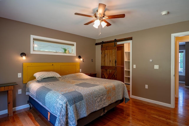 172 Hoxie Hill Rd, Orrington, ME 04474 - bedroom with a barn door, wood finished floors, a spacious closet, a ceiling fan, and a closet