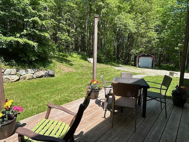 453 Canton Rd, Livermore, ME 04253 - deck featuring outdoor dining area, a lawn, an outdoor structure, and a forest view