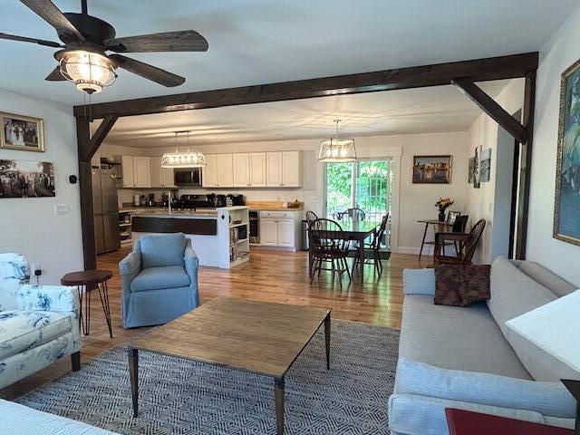 453 Canton Rd, Livermore, ME 04253 - living area featuring light wood finished floors, beamed ceiling, a ceiling fan, a chandelier, and baseboards