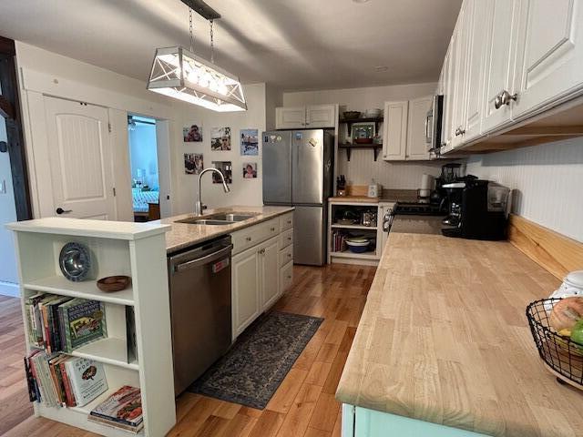 453 Canton Rd, Livermore, ME 04253 - kitchen featuring open shelves, stainless steel appliances, a sink, light countertops, and wood finished floors