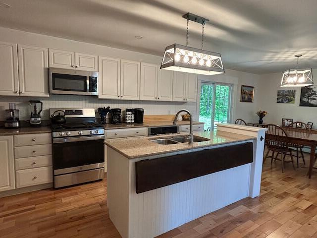 453 Canton Rd, Livermore, ME 04253 - kitchen with stainless steel appliances, a sink, white cabinets, light stone counters, and light wood finished floors