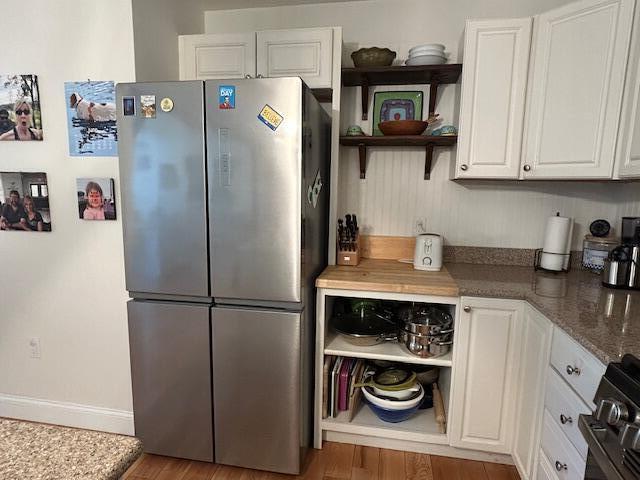 453 Canton Rd, Livermore, ME 04253 - kitchen with freestanding refrigerator, open shelves, white cabinets, wood finished floors, and range